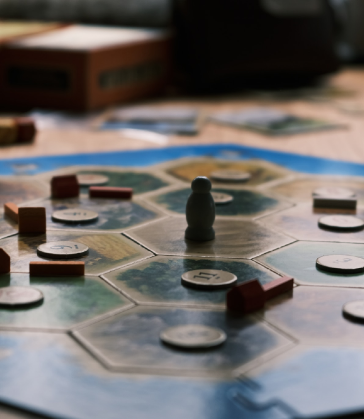 Catan game board and game pieces on a table in the middle of a game